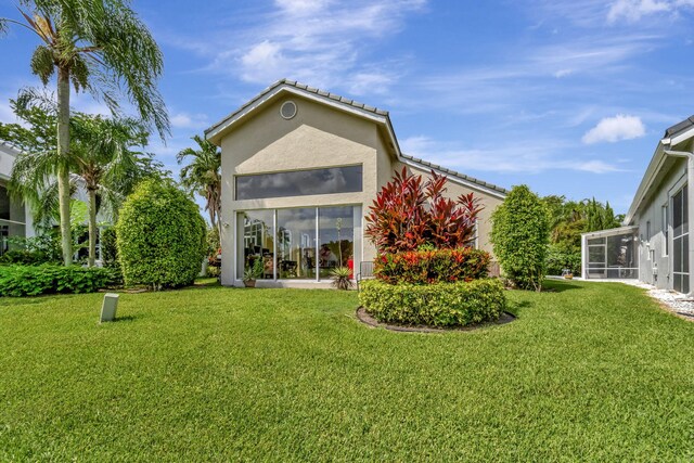 rear view of house with a sunroom and stucco siding