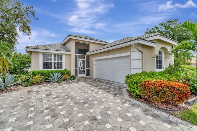 view of front of house with a garage, decorative driveway, a tile roof, and stucco siding