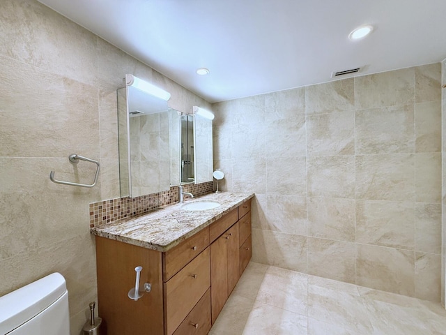 bathroom featuring decorative backsplash, toilet, tile walls, and vanity