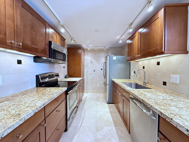 kitchen featuring light stone countertops, stainless steel appliances, tasteful backsplash, and sink