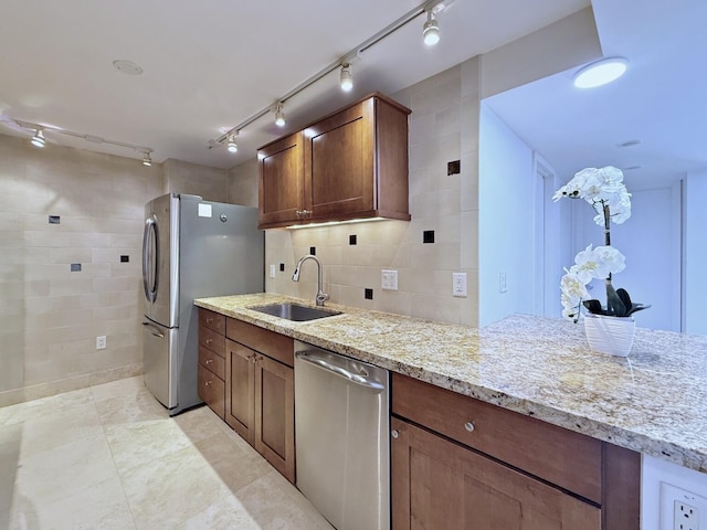 kitchen with sink, decorative backsplash, light tile patterned floors, light stone countertops, and appliances with stainless steel finishes