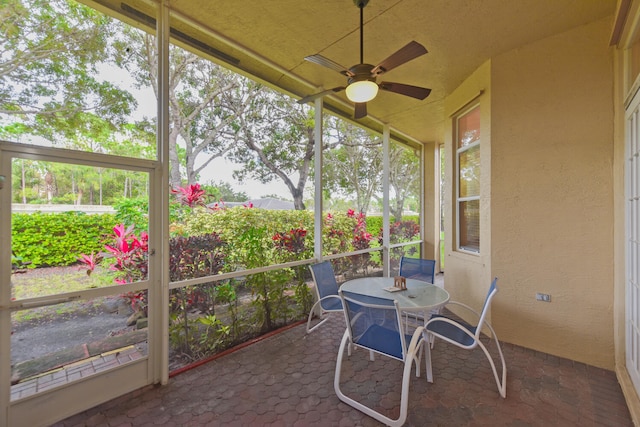 unfurnished sunroom featuring ceiling fan