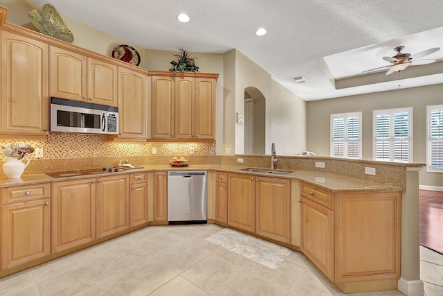 kitchen with sink, ceiling fan, light stone counters, kitchen peninsula, and stainless steel appliances