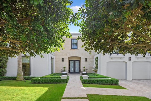 view of front facade featuring a front lawn, a garage, and french doors