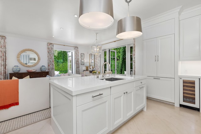 kitchen with a center island with sink, white cabinetry, beverage cooler, and sink