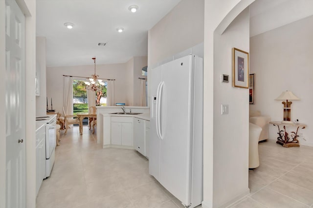 kitchen featuring white appliances, vaulted ceiling, hanging light fixtures, an inviting chandelier, and white cabinets