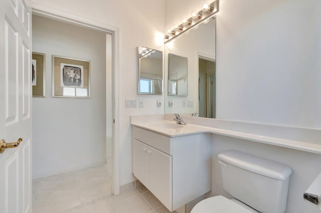 bathroom with toilet, vanity, and tile patterned floors