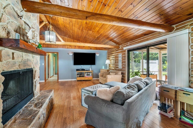 living room with beam ceiling, a stone fireplace, rustic walls, and light hardwood / wood-style flooring