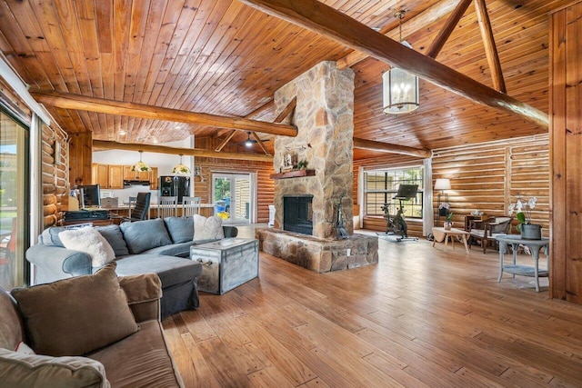 living room featuring light wood-type flooring, rustic walls, beam ceiling, high vaulted ceiling, and a stone fireplace