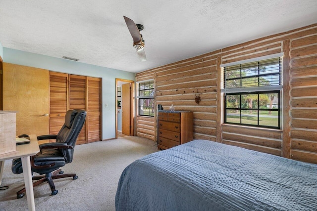 carpeted bedroom with log walls, a closet, and ceiling fan