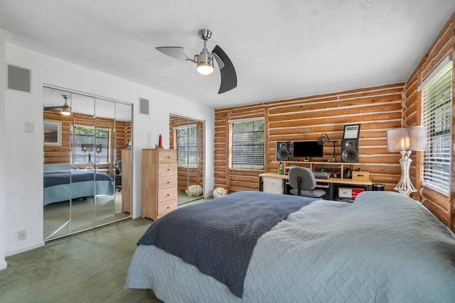 bedroom with log walls, a textured ceiling, carpet floors, and ceiling fan