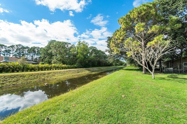 view of property's community with a lawn and a water view