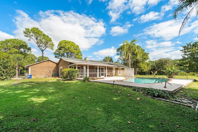 back of property with a sunroom, a lawn, and central AC