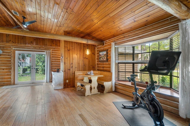 exercise area with light wood-type flooring, vaulted ceiling, rustic walls, and wooden ceiling