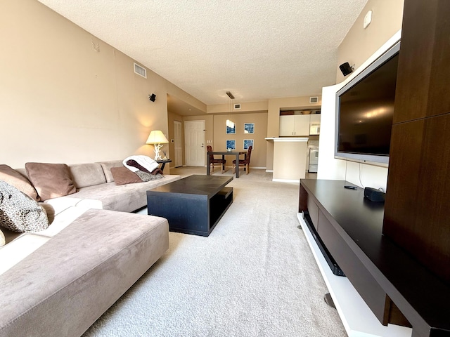 living area featuring carpet floors, visible vents, a textured ceiling, and baseboards