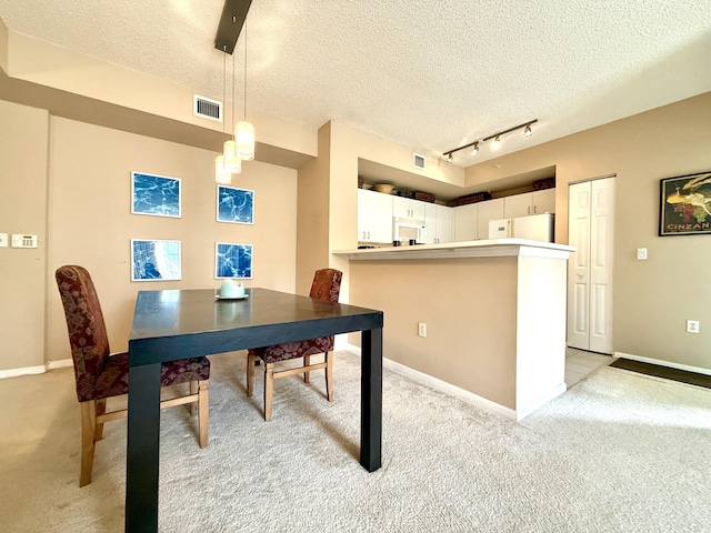 dining area featuring light colored carpet, visible vents, and a textured ceiling