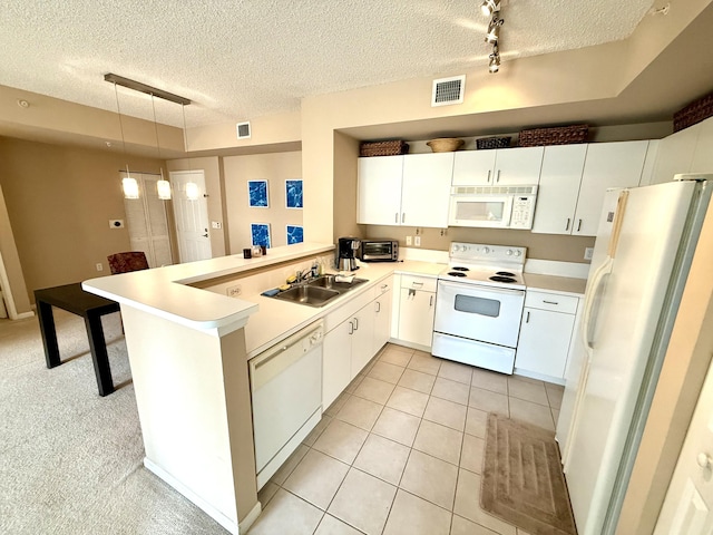 kitchen with a peninsula, white appliances, light countertops, and pendant lighting