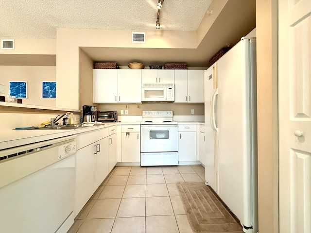 kitchen with light tile patterned floors, a textured ceiling, white appliances, white cabinetry, and light countertops