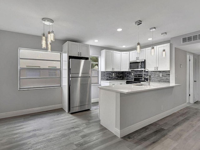 kitchen with white cabinets, decorative light fixtures, stainless steel appliances, and kitchen peninsula