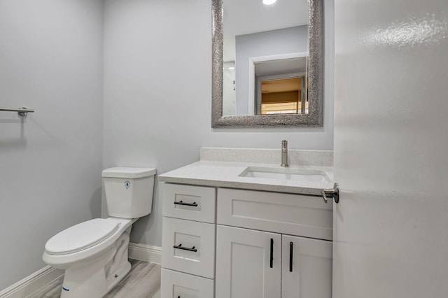 bathroom with hardwood / wood-style floors, vanity, and toilet