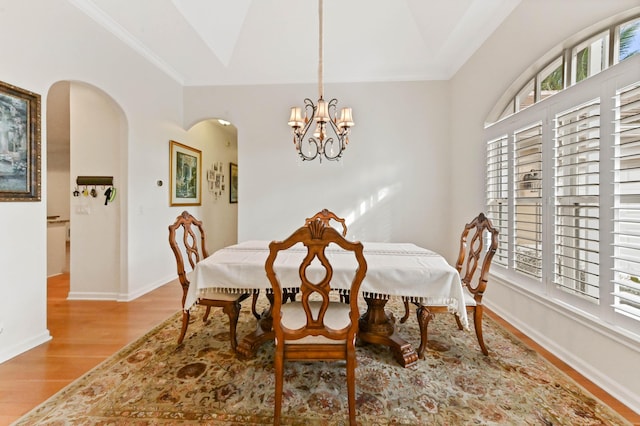 dining room with crown molding, vaulted ceiling, light hardwood / wood-style floors, and a chandelier