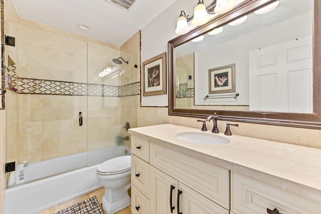 full bathroom with bath / shower combo with glass door, vanity, a textured ceiling, tile patterned floors, and toilet