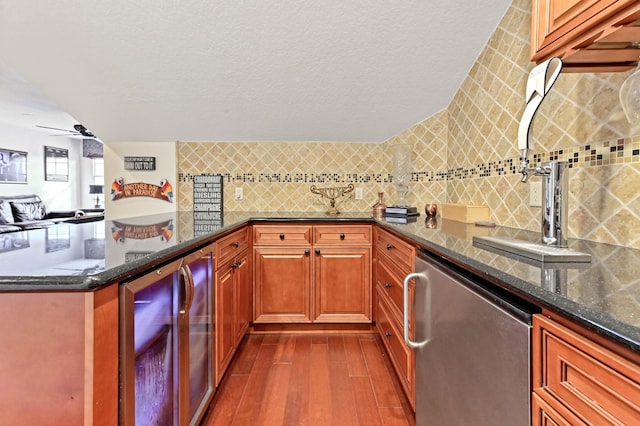 kitchen featuring wine cooler, dark stone counters, stainless steel dishwasher, ceiling fan, and dark wood-type flooring