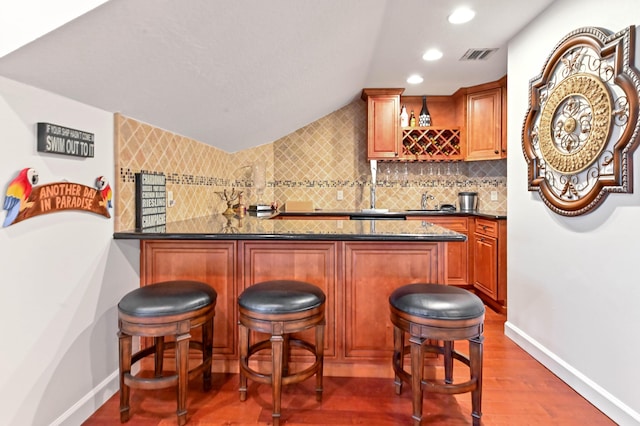 bar featuring dark stone countertops, dark hardwood / wood-style flooring, and decorative backsplash