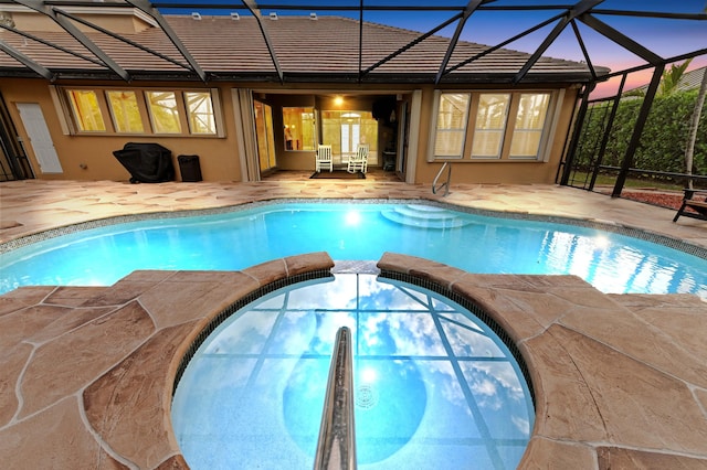 pool at dusk featuring a lanai and a patio