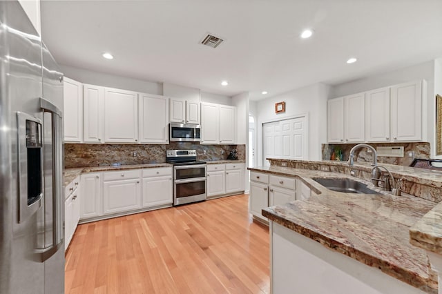 kitchen featuring sink, light stone countertops, white cabinets, and appliances with stainless steel finishes