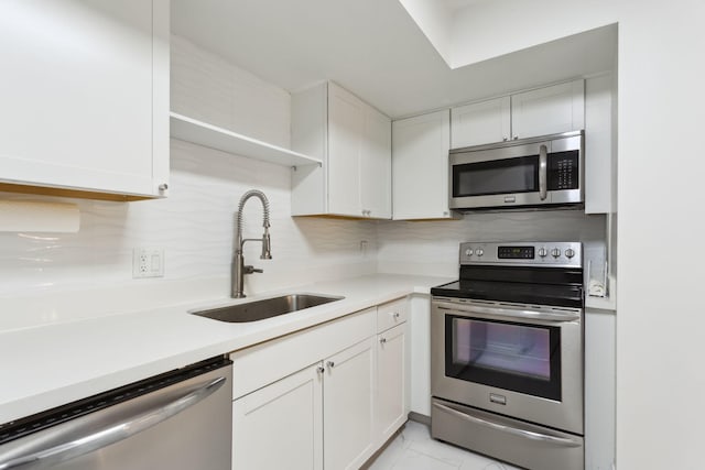 kitchen featuring decorative backsplash, stainless steel appliances, white cabinetry, and sink