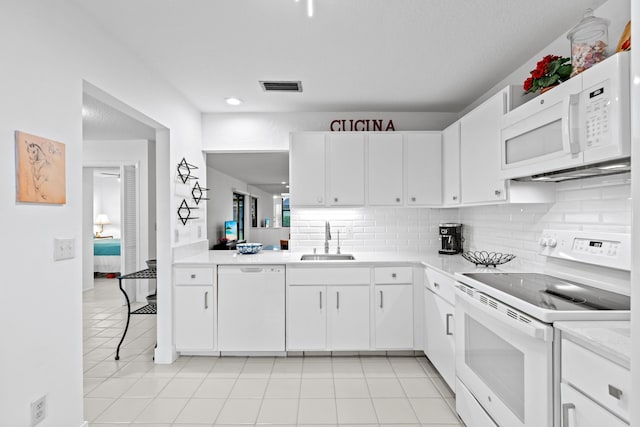 kitchen with light tile patterned floors, sink, white appliances, and white cabinets