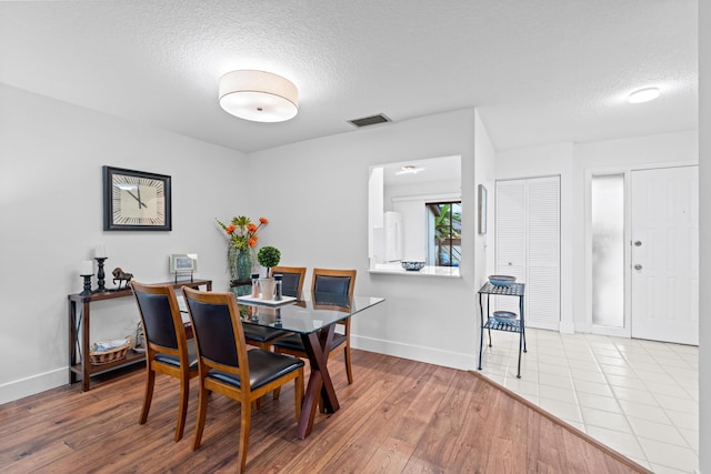 dining area featuring a textured ceiling and light hardwood / wood-style floors