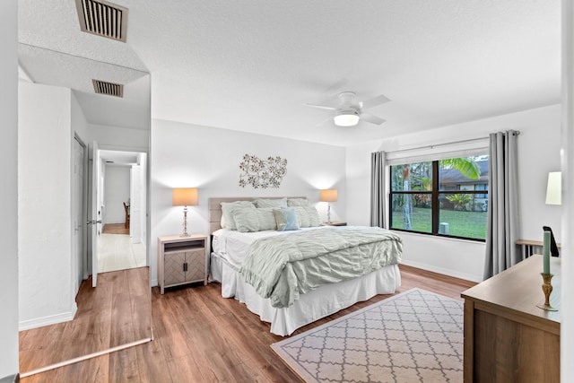 bedroom with ceiling fan, hardwood / wood-style floors, and a textured ceiling