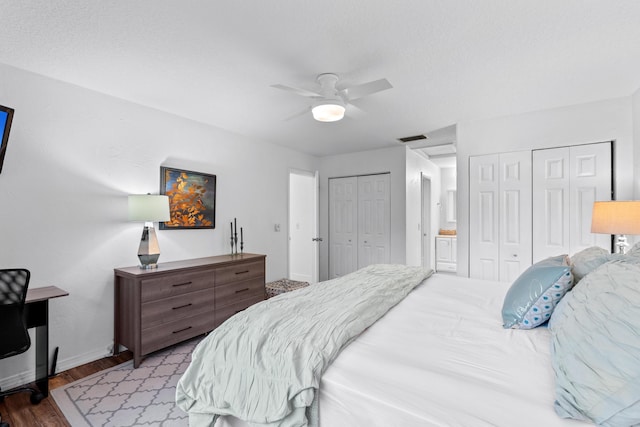 bedroom with a textured ceiling, ceiling fan, light hardwood / wood-style flooring, and multiple closets