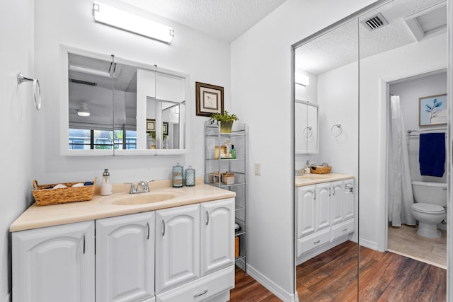 bathroom with hardwood / wood-style flooring, a textured ceiling, toilet, and vanity