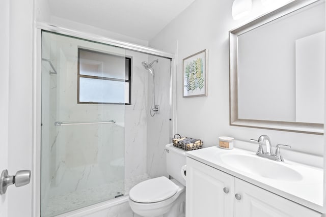 bathroom with toilet, vanity, and a shower with shower door