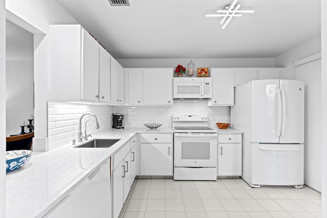 kitchen with tasteful backsplash, sink, white appliances, white cabinetry, and light tile patterned floors