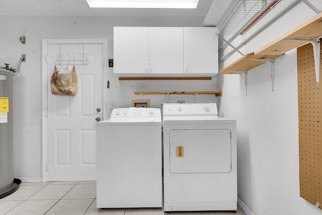 clothes washing area featuring cabinets, separate washer and dryer, and light tile patterned floors