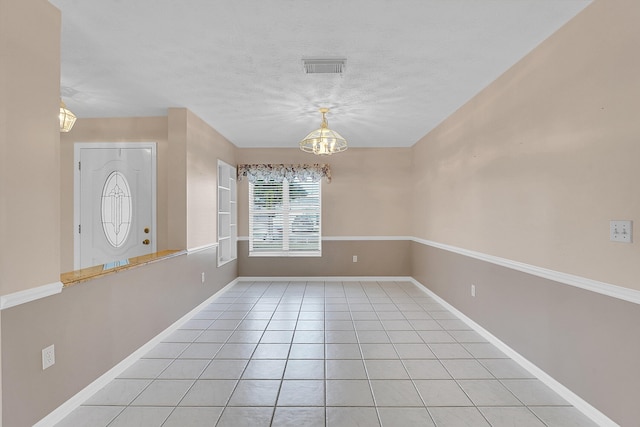 tiled spare room featuring a notable chandelier