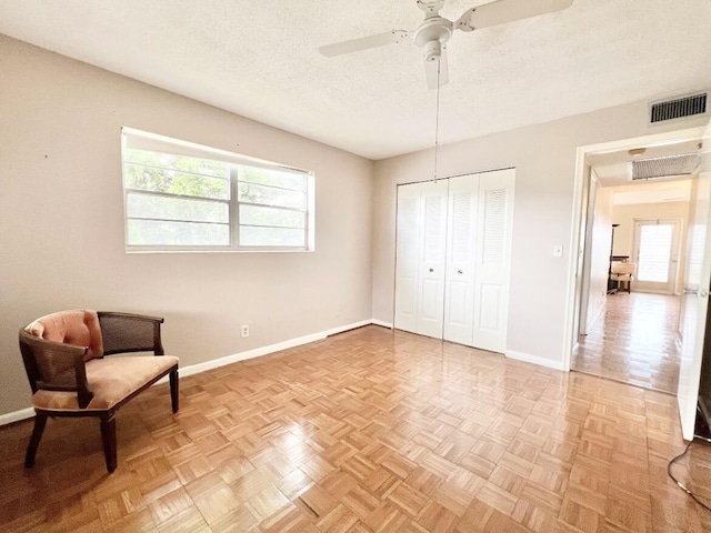 living area featuring plenty of natural light, ceiling fan, a textured ceiling, and light parquet floors