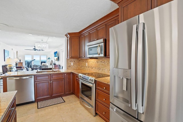 kitchen with sink, tasteful backsplash, light stone counters, light tile patterned floors, and appliances with stainless steel finishes