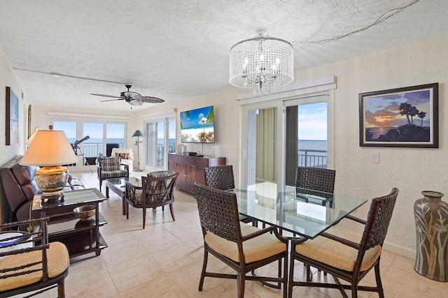 tiled dining area featuring ceiling fan with notable chandelier and a textured ceiling