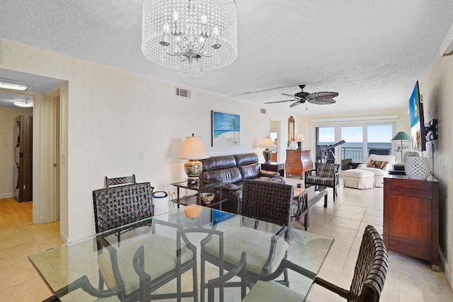 dining space featuring ceiling fan with notable chandelier, light tile patterned flooring, and a textured ceiling