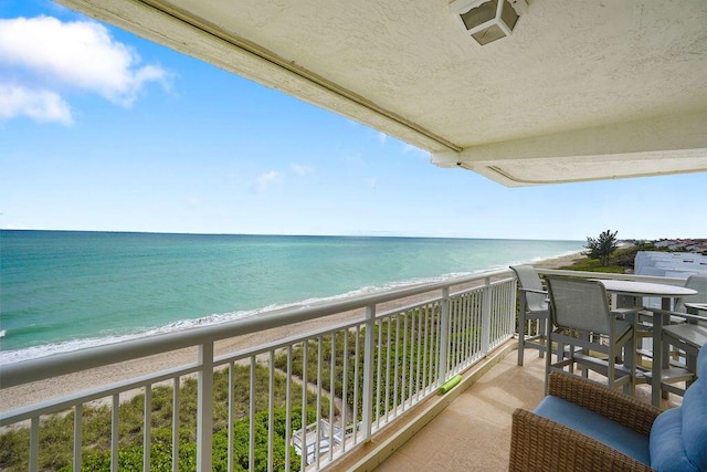 balcony featuring a view of the beach and a water view