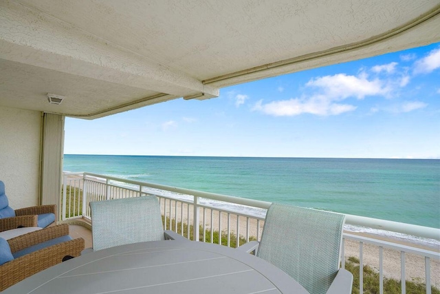 balcony featuring a water view and a beach view