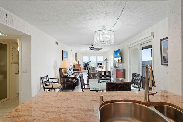 kitchen with a textured ceiling, ceiling fan with notable chandelier, and sink