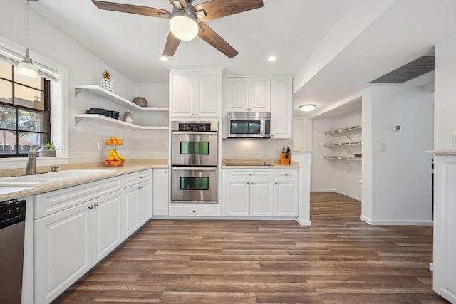 kitchen with hanging light fixtures, stainless steel appliances, tasteful backsplash, white cabinetry, and sink