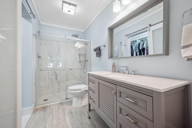 bathroom featuring hardwood / wood-style floors, toilet, vanity, ornamental molding, and a shower with door