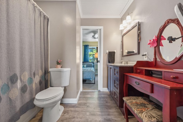 bathroom with toilet, wood-type flooring, vanity, ornamental molding, and ceiling fan